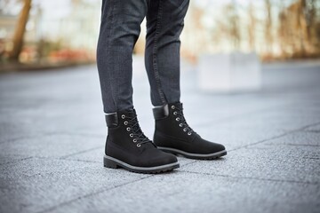 A pair of stylish dark brown leather boots paired with grey denim jeans captures the essence of modern urban fashion.