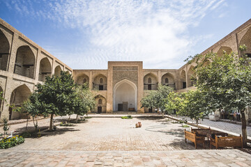 The courtyard of an ancient madrasah in the ancient city of Bukhara in Uzbekistan in oriental style, ancient oriental buildings - obrazy, fototapety, plakaty