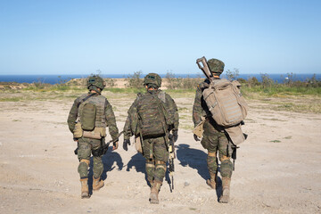 Tres militares armados de uniforme se dirigen a su posición durante unos ejercicios militares.