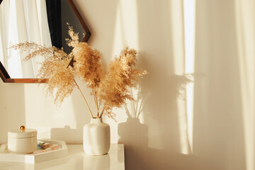 Light and airy modern interior, with decorative pampass grass in a vase in a sunset light