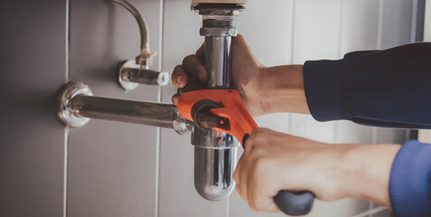 plumber at work in a bathroom, plumbing repair service , fix water plumbing leaks, replace the...