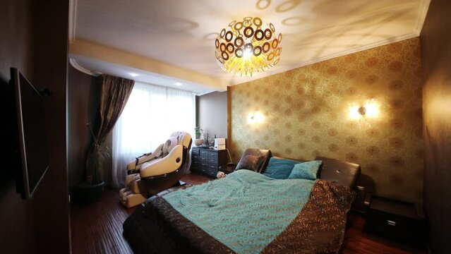 Turning on and off light in empty cozy bedroom with big double bed