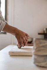 Detailed view of a potter's hands as they skillfully shape a piece of clay on a plaster bat in a sunlit studio