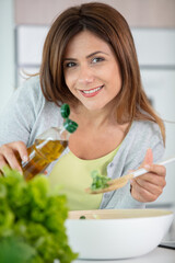 Obraz na płótnie Canvas woman at home pouring dressing on salad