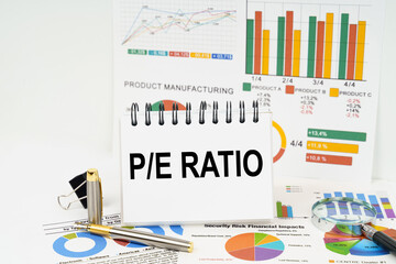 On the table are reports with graphs and a notepad with the inscription - Price-to-Earnings ratio