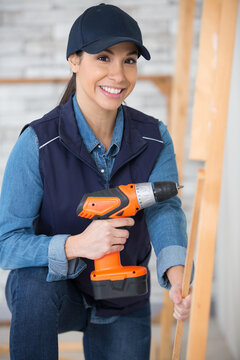 female worker using drill on wooden pieces