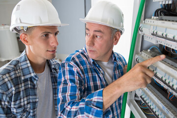 electrician pointing at the switch to his apprentice