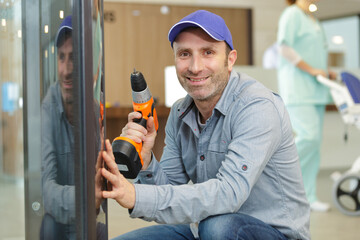 handyman with drill mounting equipment in clinic