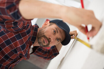 man measuring wall with a tape measure