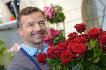 portrait of male florist holding bunch of red roses