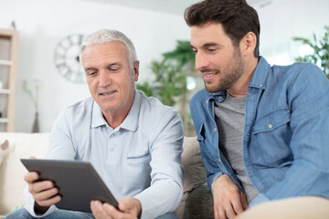 senior man using tablet pc with his adult son