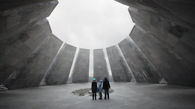 Family of three people is standing at the eternal flame in memorial complex