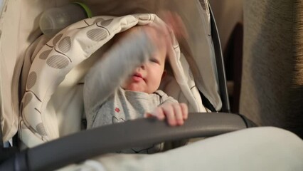 Baby in bassinet waving hands and beat handle close up in Armenia.