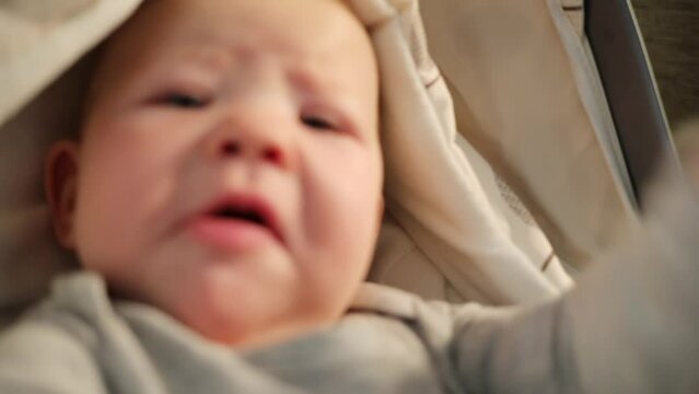 Face of baby with drop on cheek waving hands in bassinet close up in Armenia.