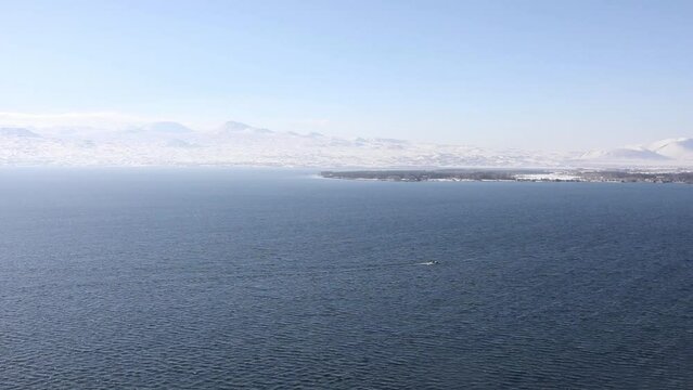 Alone boat on lake Sevan afar and mountains in Armenia in winter sunny day.