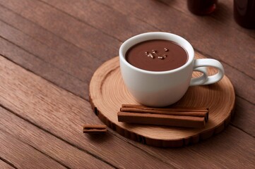Cup of hot chocolate with cinnamon on wooden table, closeup