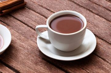 Cup of hot chocolate with cinnamon on wooden table, closeup