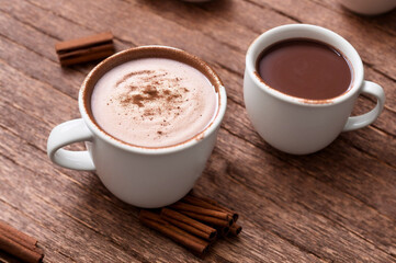 Fototapeta premium Cup of hot chocolate with cinnamon on wooden table, closeup