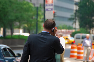 Close up view of a business man in suit seen on the back while talking on a cellphone or mobile...