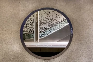 Fototapeten Rotterdam, The Netherlands  View through a round opening in out of focus concrete wall of the Wilhelminaplein subway station with platform and escalator on other side © Sonja