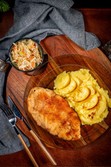 Breaded chicken breast fillet served with boiled potatoes and salad.