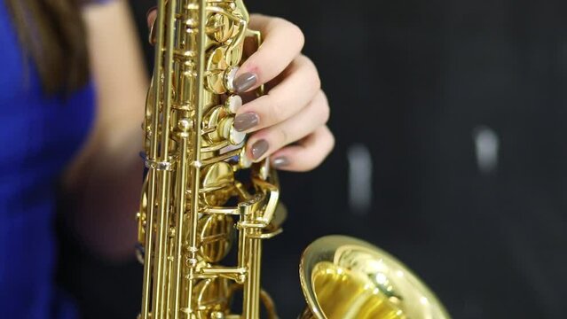 Hands of a woman pressing keys on a saxophone while playing