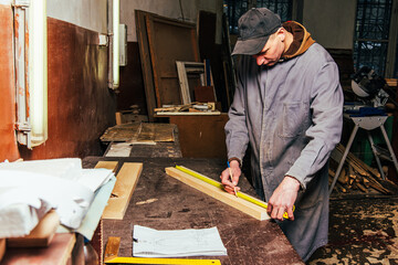 A carpenter works in a workshop with a saw, planer and various tools