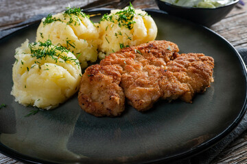 Pork chop served with mashed potatoes and cucumber salad.