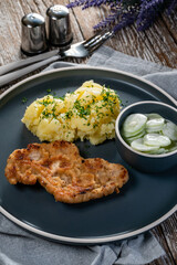 Pork chop served with mashed potatoes and cucumber salad.