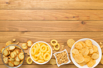 Various unhealthy snacks on wooden background, top view