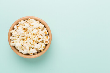 Bowl with popcorn on color background, top view