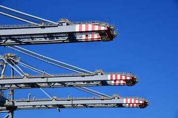 Low angle close up view of gantry cranes sticking against the blue sky waiting for handling ‘ship...