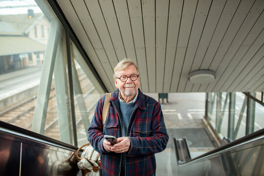Senior man using a smartphone in a train station