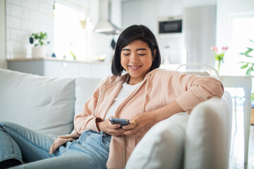 Young asian woman using a smartphone on a couch
