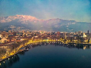 Drone shot of the lakefront of Lecco and Lake Como at dusk, Italy. Mount Resegone in the background
