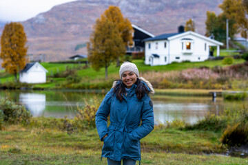 mujer latina sonriendo en paisaje noruego con ropa de invierno
