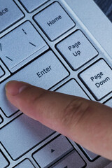 Finger pressing an enter key. Computer user hitting the enter key, up close. Confirmation, sending a message.
