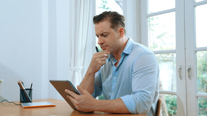 Businessman struggle to solve work problem from home using laptop, sitting on his desk at home...