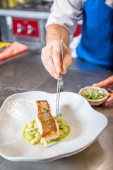Chef cocina lomo de merluza a la plancha con judías verdes verdinas guisadas en un plato blanco de...