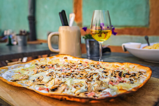 Flammekueche or tarte flambee with fromage blanc cheese bacon and mushrooms, a glass of white wine at an outdoor restaurant, Riquewihr, Alsace, France