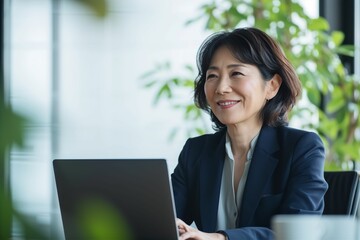 パソコンに向かって笑う年配の日本人女性（打ち合わせ・商談・リモート会議）