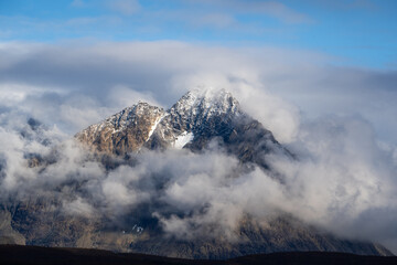 Montaña con nublada con nieve y rallos de sol amarillos
