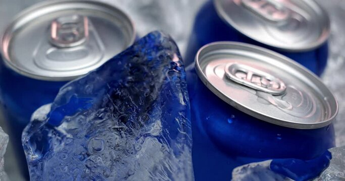 The drink is cooled with ice in a metal can. Beer in aluminum cans was placed in ice. Pieces of ice fall into a container with drinks.