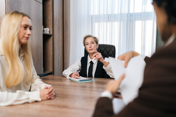 Sad couple writing documents with lawyer in agreement, application or signing legal paperwork at office. Married man and woman filing divorce, shares or mortgage assets with attorney at desk.