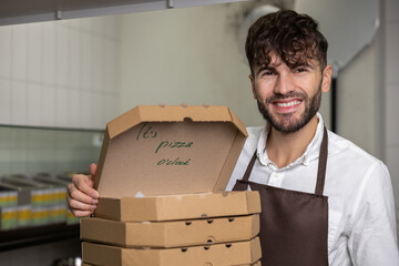 Male service man with many pizza boxes in pizzeria - obrazy, fototapety, plakaty