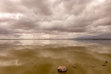 dramatic sky is reflecting in the water surface of a lake in Amboseli NP