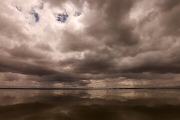 dramatic sky is reflecting in the water surface of a lake in Amboseli NP