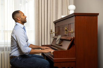Man sitting at piano and playing at home using tablet