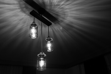 Black and white hanging dangling ceiling scones in front of a dark background