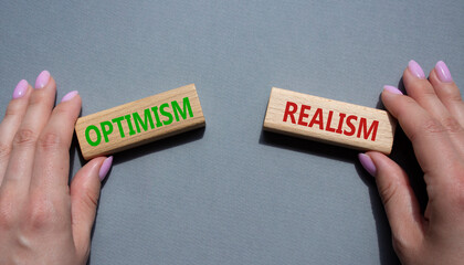 Optimism or Realism symbol. Concept word Optimism or Realism on wooden blocks. Businessman hand. Beautiful grey background. Business and Optimism or Realism concept. Copy space